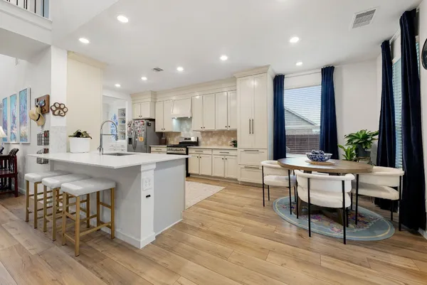 a kitchen with a table chairs wooden floors and a view of living room