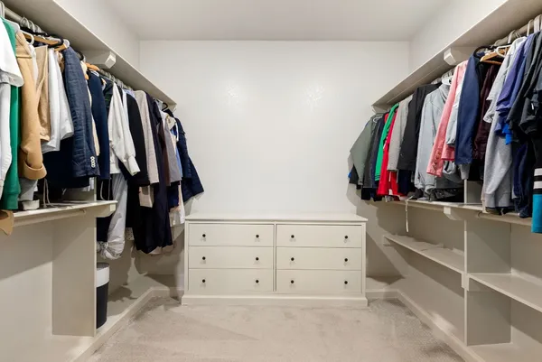 a view of walk in closet with clothes and shoes