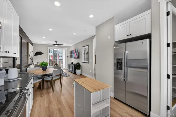 a kitchen with stainless steel appliances kitchen island granite countertop a refrigerator a stove and a dining table with wooden floor