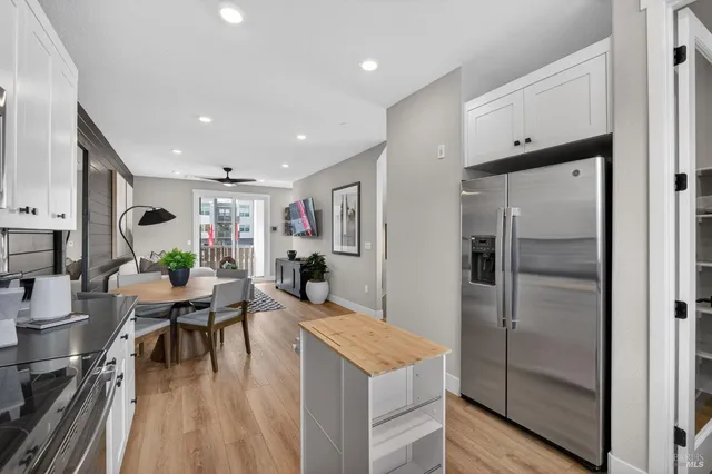 a kitchen with stainless steel appliances kitchen island granite countertop a refrigerator a stove and a dining table with wooden floor