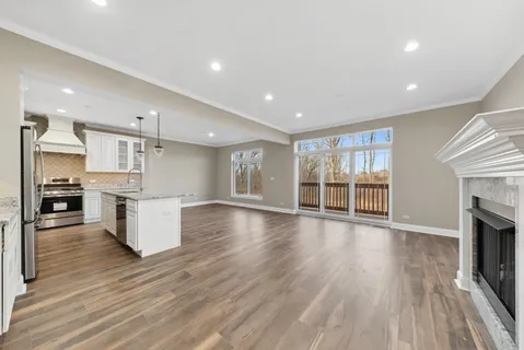 an open kitchen with white cabinets wooden floor and stainless steel appliances