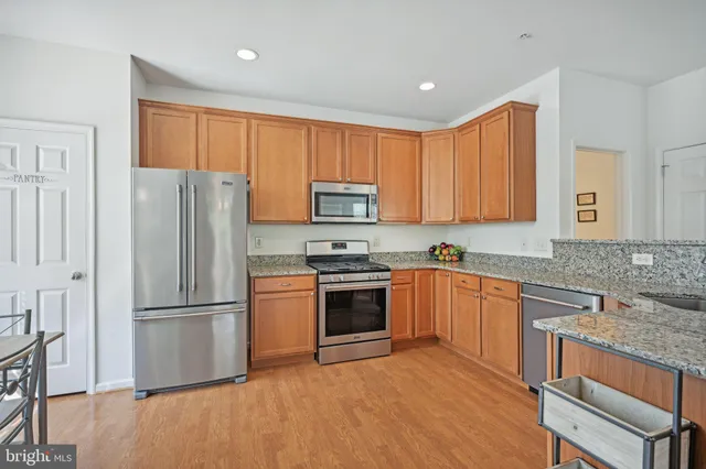 a kitchen with granite countertop wooden floors stainless steel appliances and a counter space