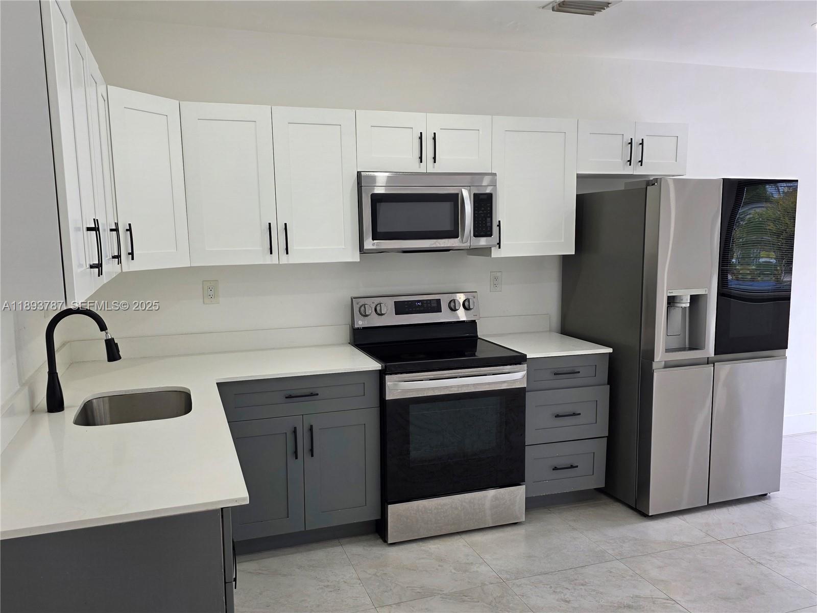 1102 Northwest 103rd Street Miami, FL 33150 - Photo 3 of 37 a kitchen with stainless steel appliances granite countertop a refrigerator stove a sink and dishwasher