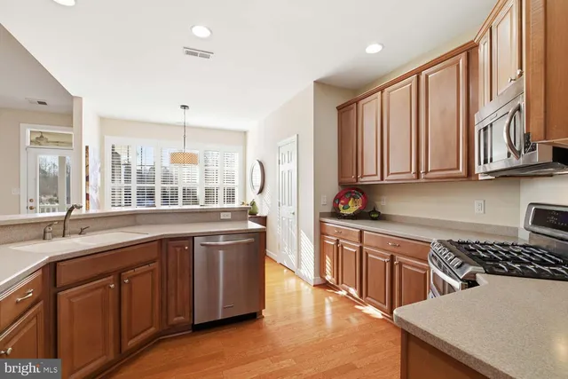 a kitchen with stainless steel appliances granite countertop a stove a sink dishwasher and cabinets with wooden floor