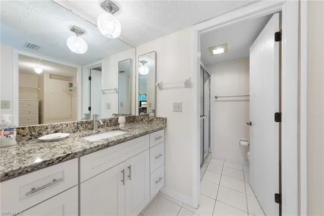 a bathroom with a granite countertop double vanity sink and mirror
