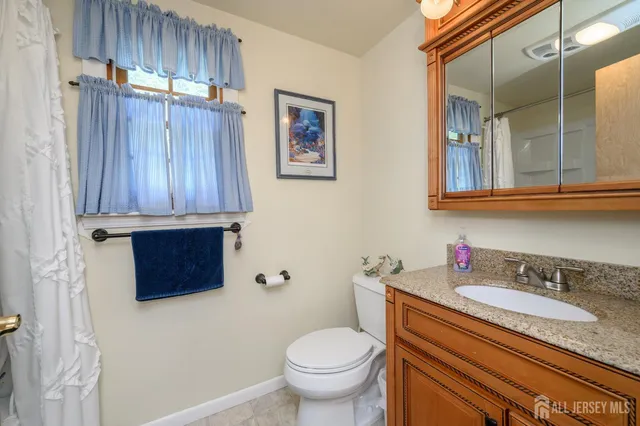 a bathroom with a granite countertop sink a toilet and a mirror