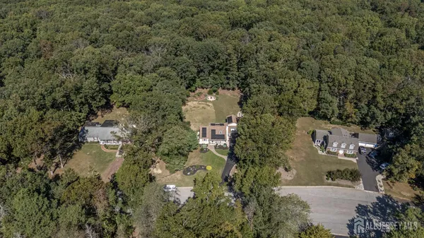 an aerial view of residential house with outdoor space and trees all around