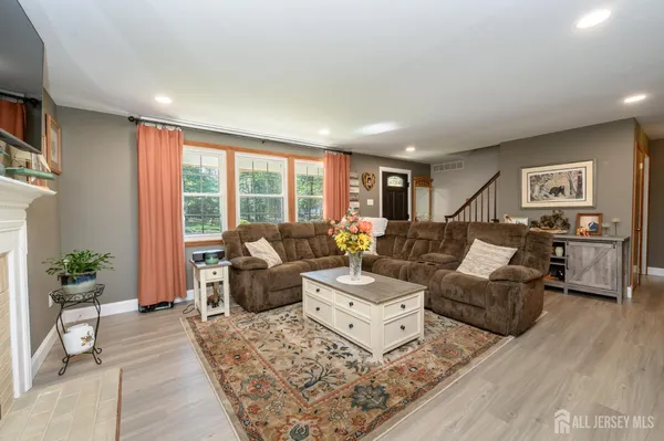 a living room with furniture large window and wooden floor