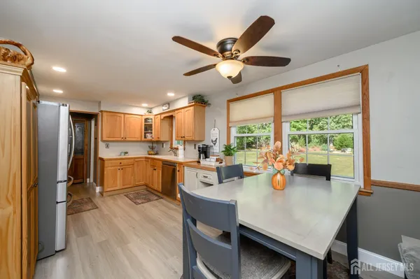a kitchen with a refrigerator a sink dishwasher a dining table and chairs with wooden floor