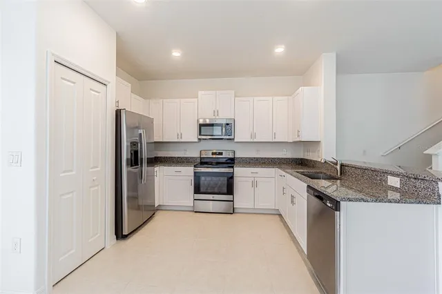 a kitchen with stainless steel appliances granite countertop a refrigerator and a stove top oven