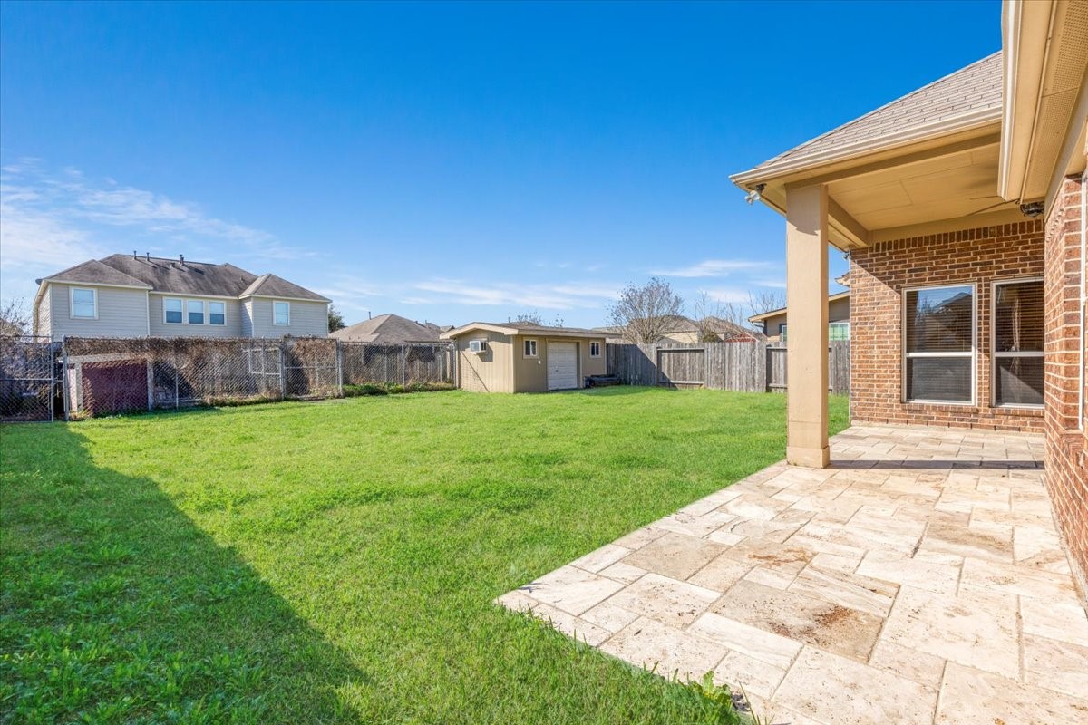 5446 Seabird Street Baytown, TX 77521 - Photo 20 of 23 The backyard features a partially covered patio, providing a perfect spot to relax or entertain while enjoying the outdoors.