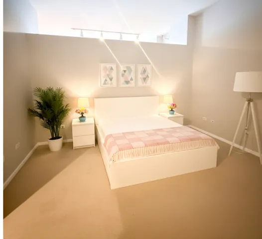 a spacious bedroom with a bed and a potted plant on the table