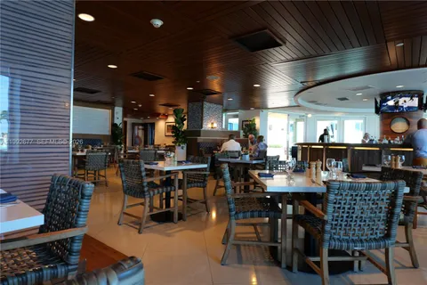 a dining hall view with a large dining table and chairs with the kitchen view