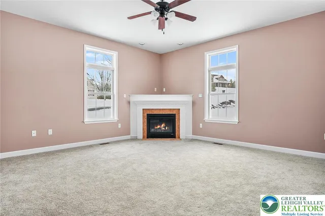 an empty room with windows and fireplace