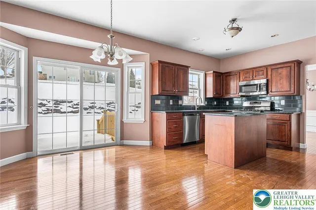 a kitchen with stainless steel appliances granite countertop a refrigerator a sink dishwasher a stove with wooden cabinets and floor