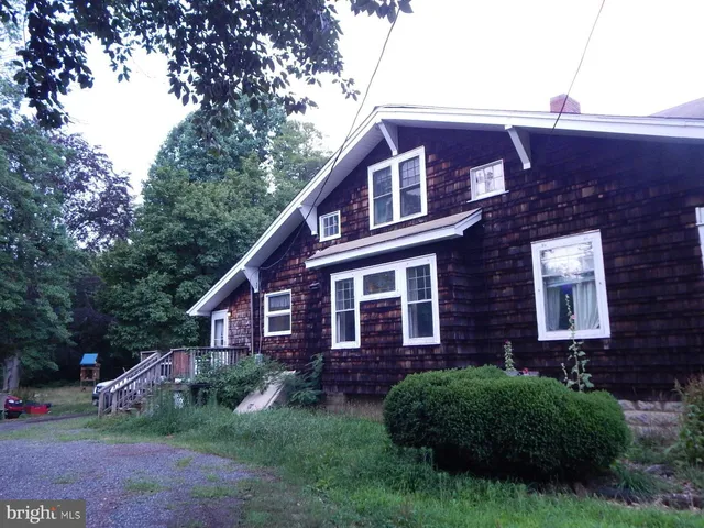 a brick house with a small yard plants and a large tree