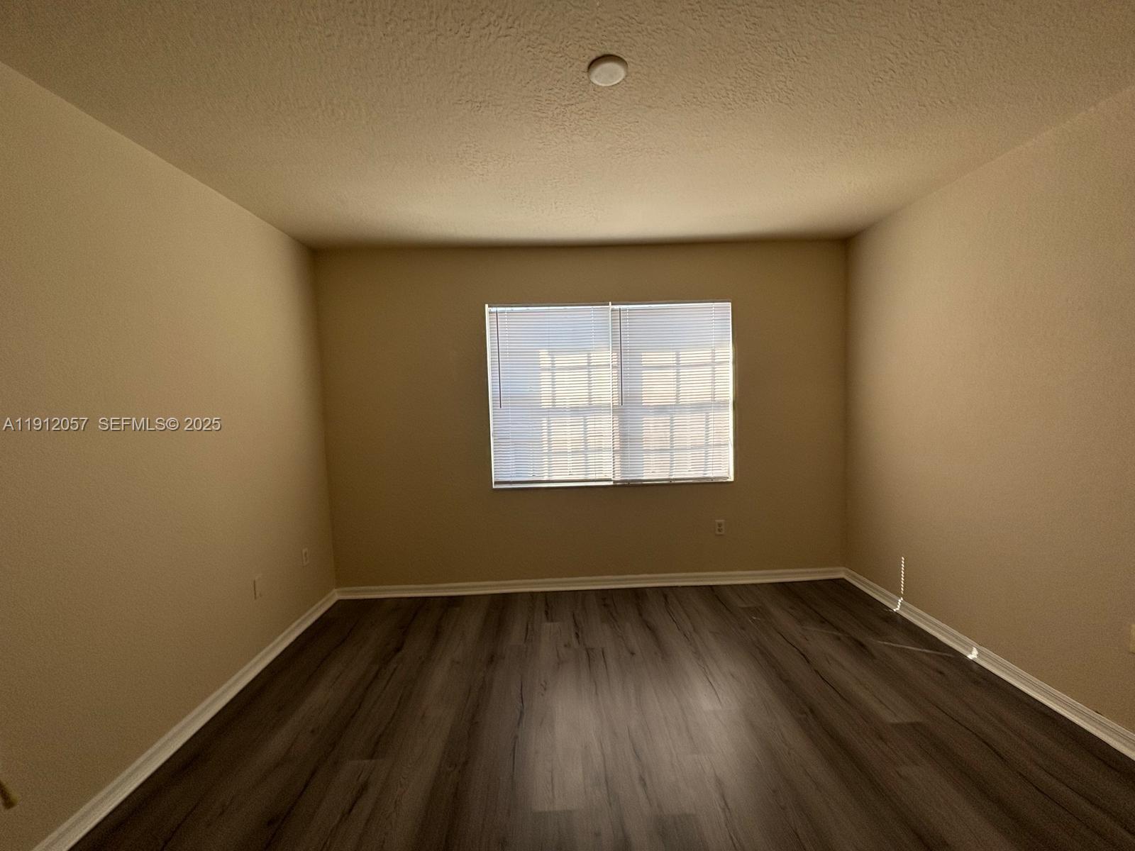 8261 Southwest 25th Court, Unit 102 Miramar, FL 33025 - Photo 12 of 15 an empty room with wooden floor and windows