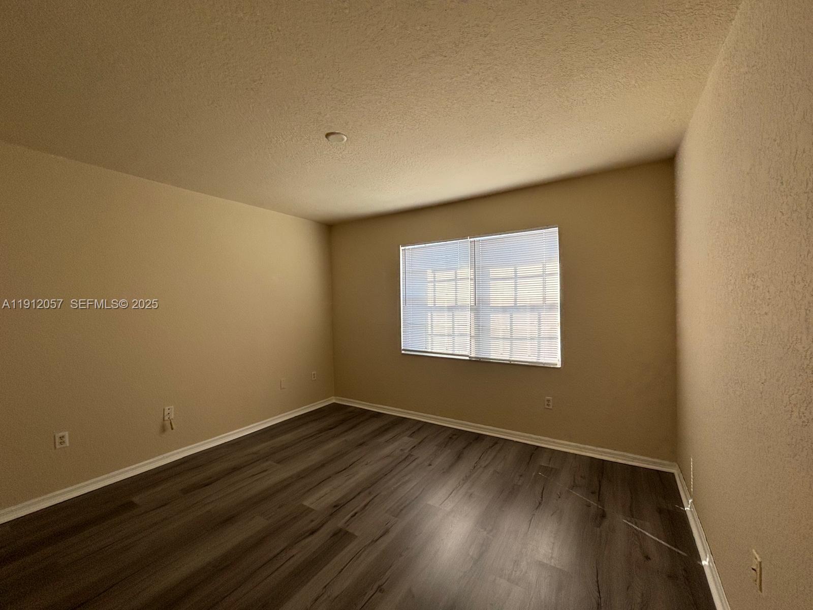 8261 Southwest 25th Court, Unit 102 Miramar, FL 33025 - Photo 15 of 15 a view of an empty room with wooden floor and a window