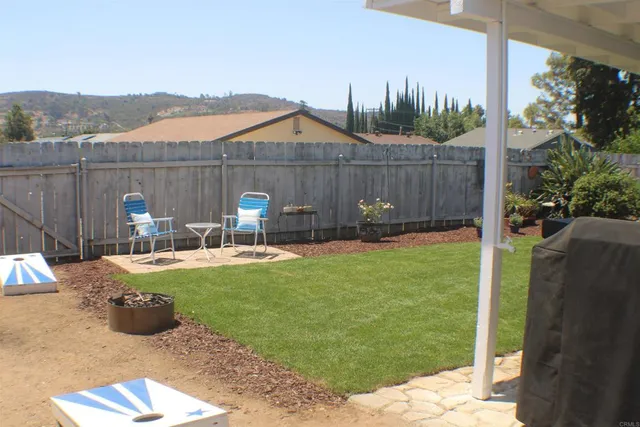 a view of a backyard with table and chairs potted plants and wooden fence