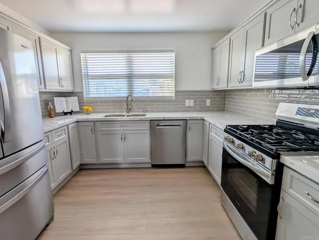 a kitchen with stainless steel appliances granite countertop a stove a sink dishwasher and a refrigerator