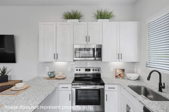 a kitchen with stainless steel appliances granite countertop a stove a sink and white cabinets