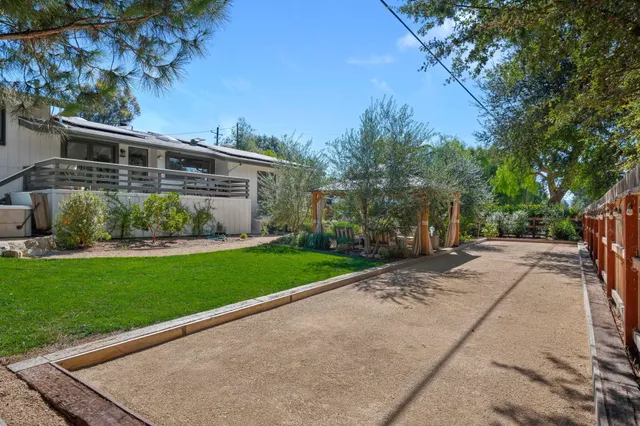 a view of a patio with table and chairs under an umbrella with large trees