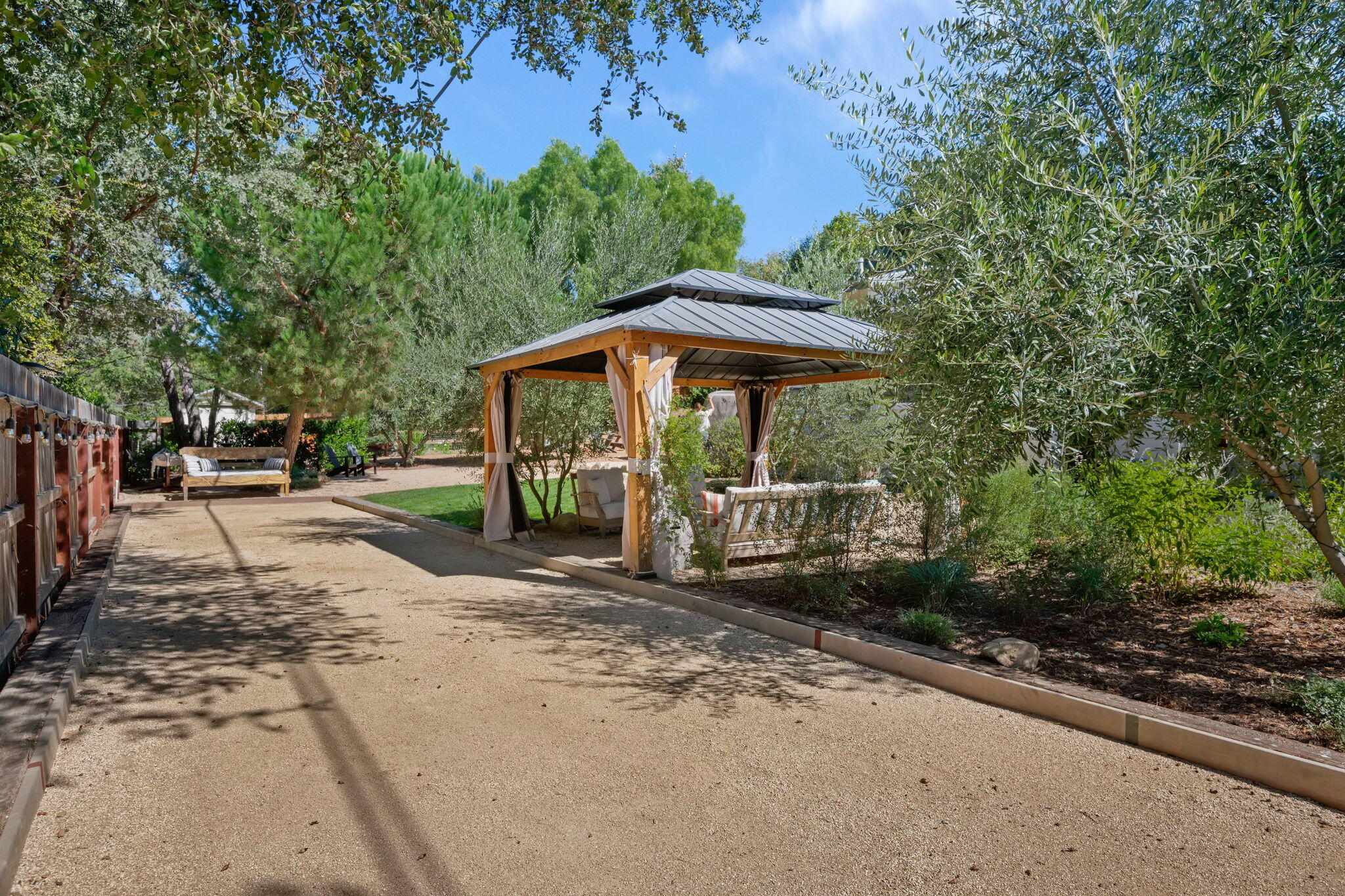 2455 Lucca Avenue Los Olivos, CA 93441 - Photo 26 of 37 a view of a patio with table and chairs under an umbrella with large trees