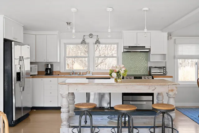 a kitchen with stainless steel appliances a dining table chairs microwave and cabinets