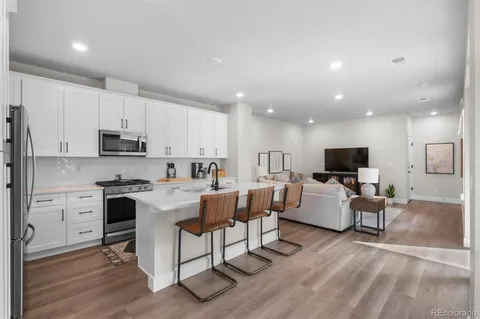 a living room with stainless steel appliances furniture and a kitchen view