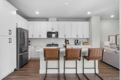 a kitchen with stainless steel appliances a refrigerator a stove a sink a dining table and chairs