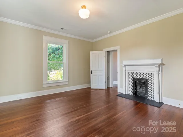an empty room with wooden floor fireplace and windows