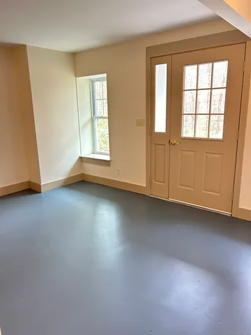 an empty room with wooden floor and windows with curtains