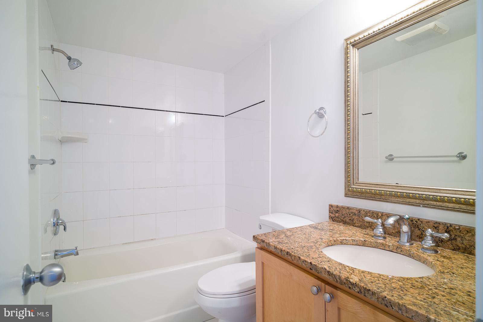 2630 Adams Mill Road Northwest, Unit 105 Washington, DC 20009 - Photo 11 of 13 a bathroom with a granite countertop sink toilet and shower