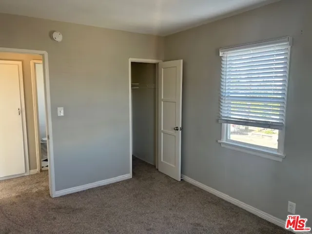 a view of an empty room with window and closet area
