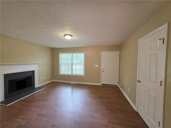 an empty room with wooden floor fireplace and windows