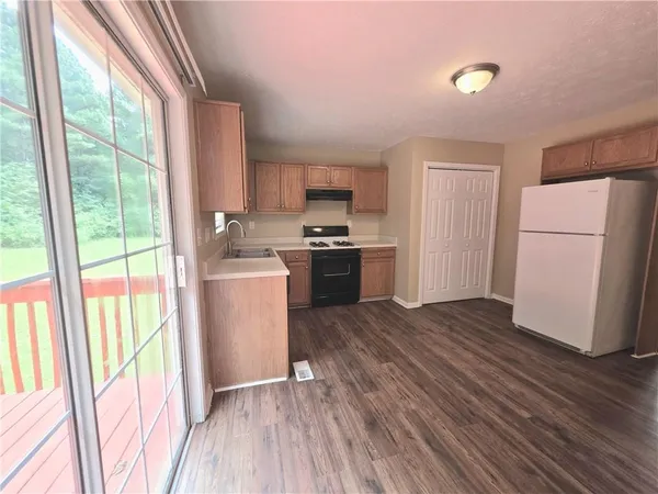 a kitchen with a refrigerator a stove top oven and a large window