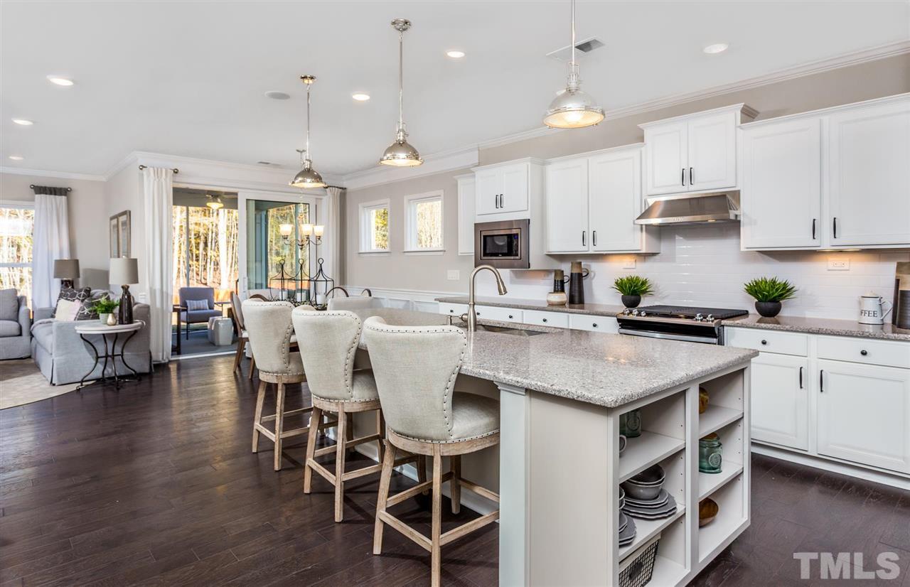 704 Haven Peak Lane Wake Forest, NC 27587 - Photo 9 of 28 a kitchen with stainless steel appliances granite countertop a stove a sink a kitchen island with a dining table and chairs