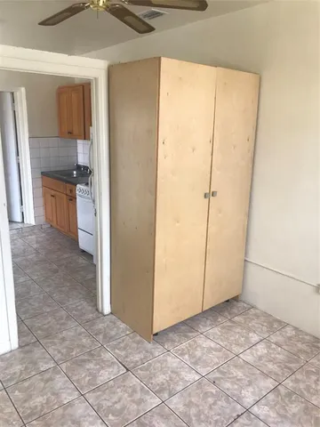 a view of a refrigerator in kitchen and an empty room