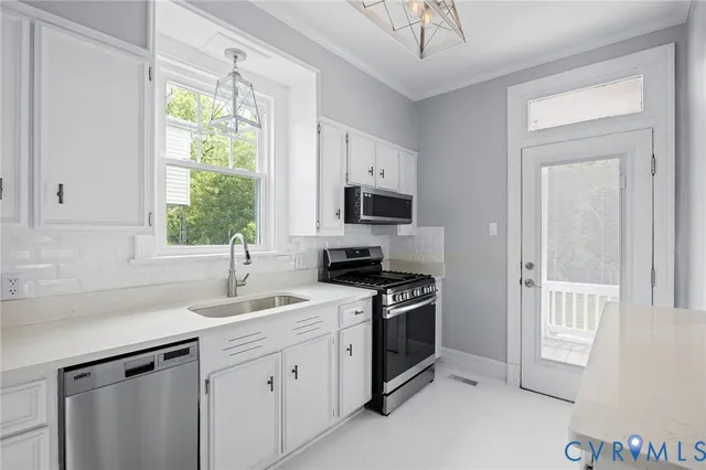 a kitchen with appliances a sink cabinets and a window