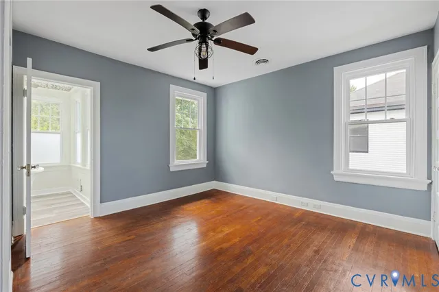 a view of empty room with wooden floor and ceiling fan