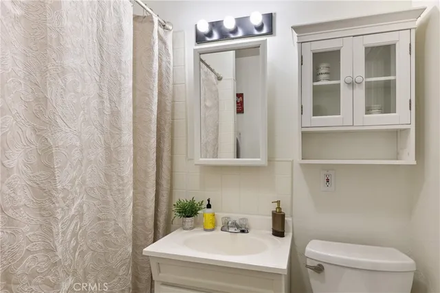 a bathroom with a granite countertop sink and a toilet