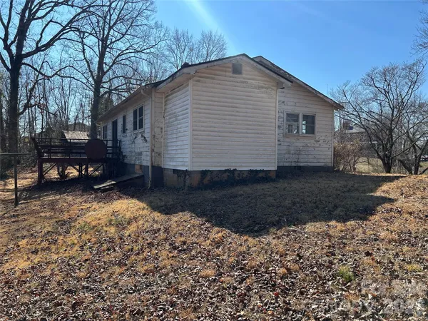 a backyard of a house with wooden fence and large trees