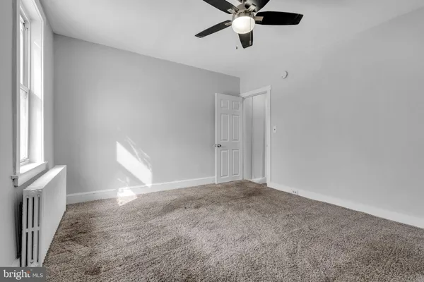 an empty room with windows and fan
