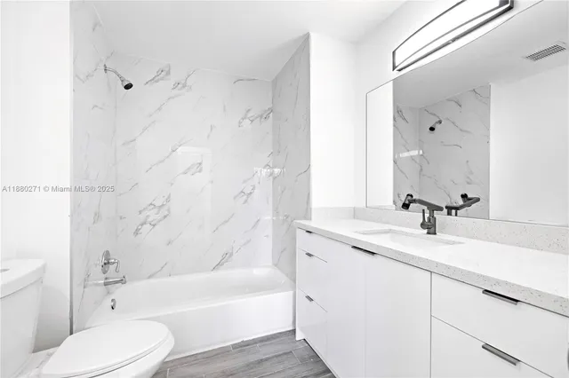 a bathroom with a granite countertop sink toilet tub and shower