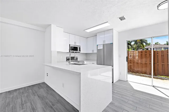 a kitchen with a sink a refrigerator a window and cabinets