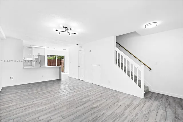 a view of an empty room with wooden floor and a ceiling fan