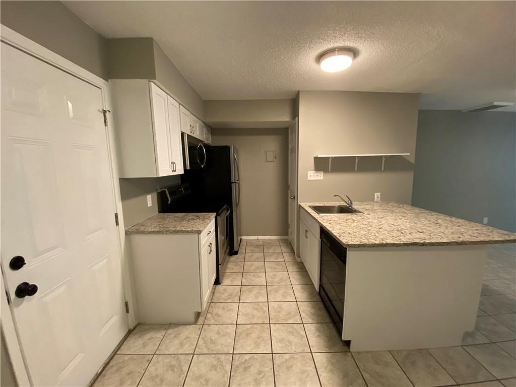 2413 Leon Street, Unit 101 Austin, TX 78705 - Photo 5 of 22 a kitchen with a sink a refrigerator and cabinets
