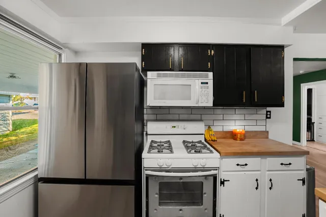 a kitchen with stainless steel appliances granite countertop a refrigerator a stove and a sink with wooden floor