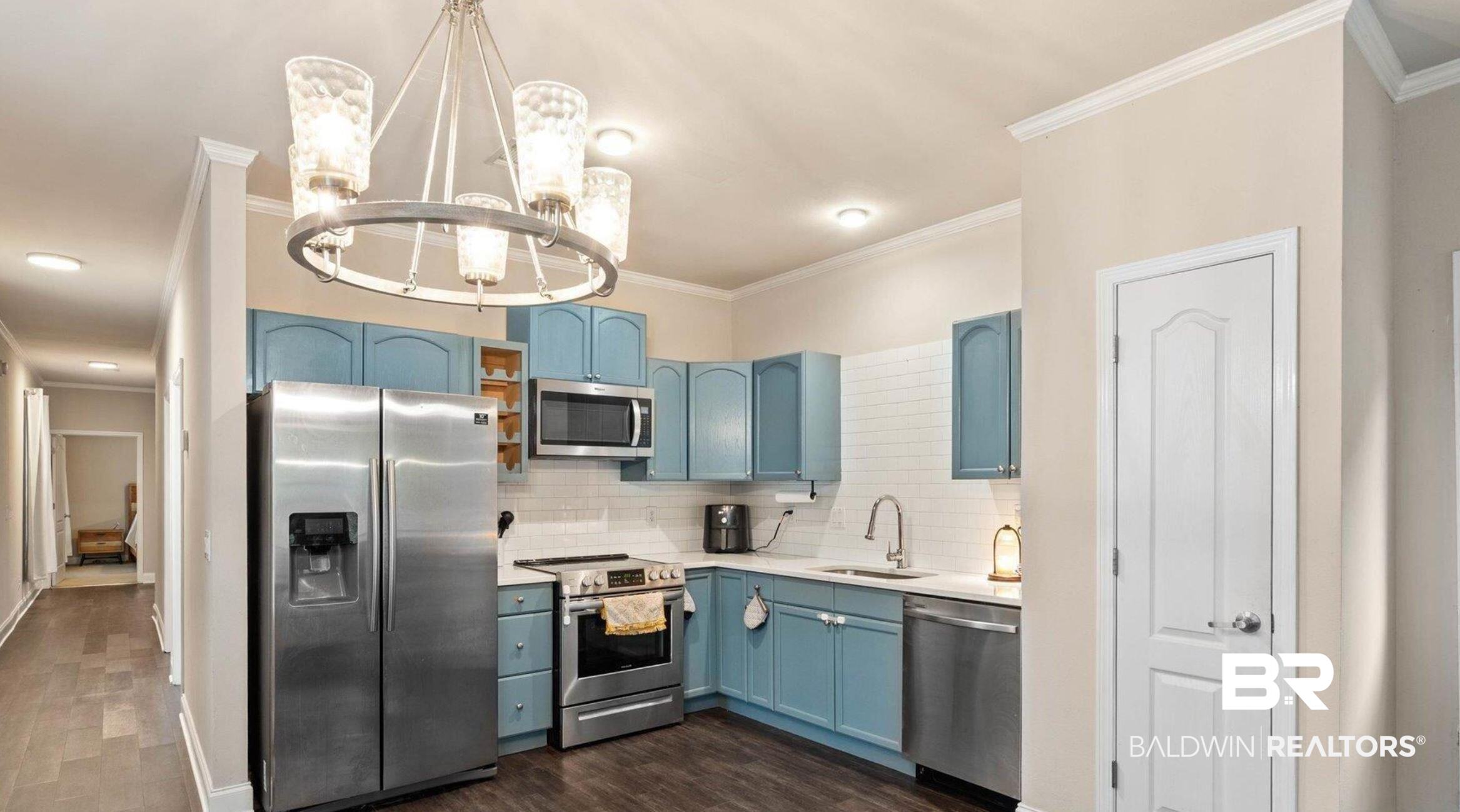25806 Pollard Road, Unit 203 Daphne, AL 36526 - Photo 4 of 14 Kitchen with blue cabinetry, appliances with stainless steel finishes, backsplash, crown molding, and hanging light fixtures