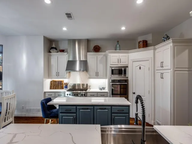 a kitchen with stainless steel appliances kitchen island granite countertop a table chairs in it and wooden floors